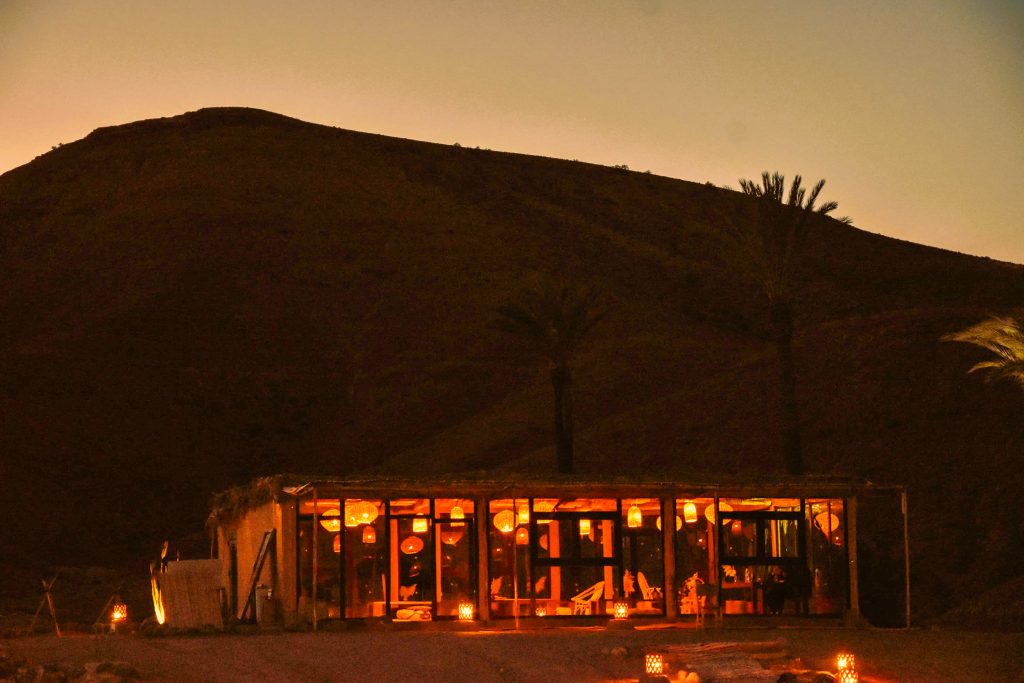 Le restaurant de l'oasis Dunes & Desert illuminé à la nuit tombée dans le désert d'Agafay
